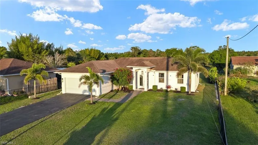 View of front of home with aphalt driveway, stucco siding, an attached garage, fence, and a front lawn