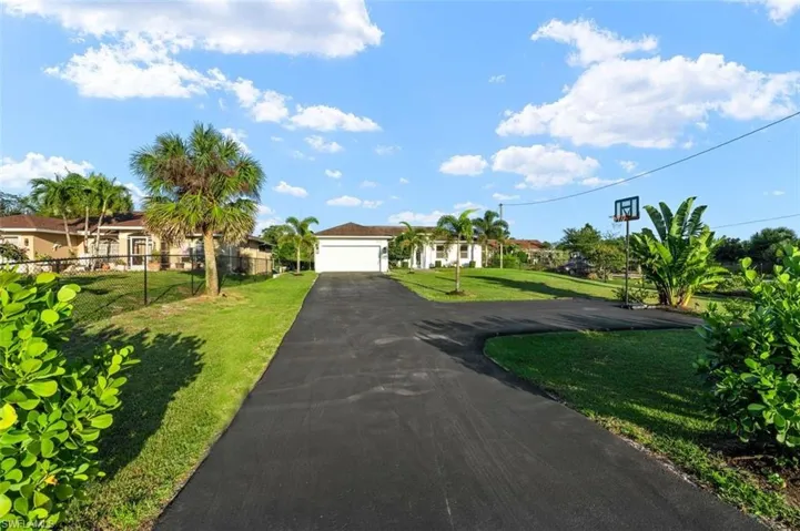 View of front of property featuring a garage, driveway, a front yard, and fence