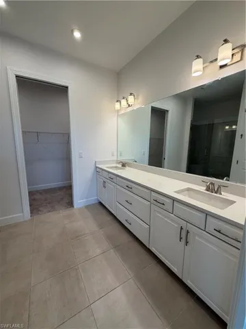 Dual vanity with white cabinetry and integrated sinks, complemented by a large mirror and coordinating light fixtures