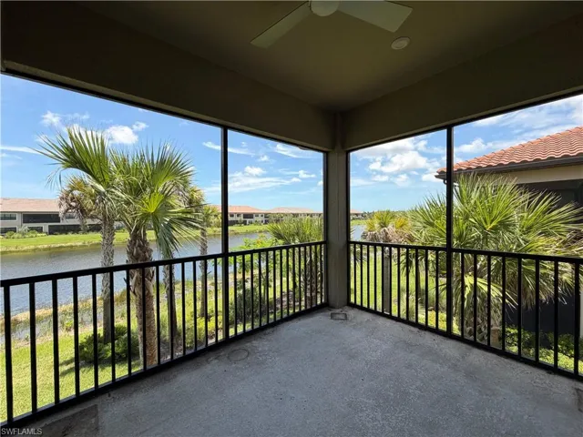 Screened lanai featuring a concrete floor, black metal railing, and an overhead ceiling fan