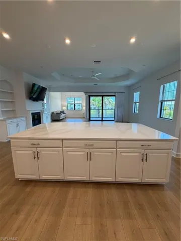 Kitchen island featuring a white countertop and white cabinetry with dark hardware