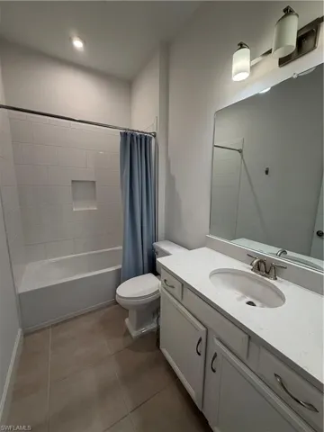Bathroom featuring a white vanity with an undermount sink, a large mirror, a chrome faucet, and a tub-shower combination with white subway tile surround and a recessed niche
