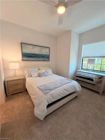 Carpeted room featuring a ceiling fan with integrated lighting, a window with horizontal blinds, and neutral wall tones