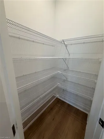 Walk-in closet with multi-level wire shelving, L-shaped configuration, and wood-finish flooring