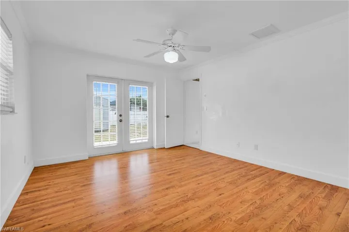 Spare room featuring crown molding, baseboards, and light wood-style flooring
