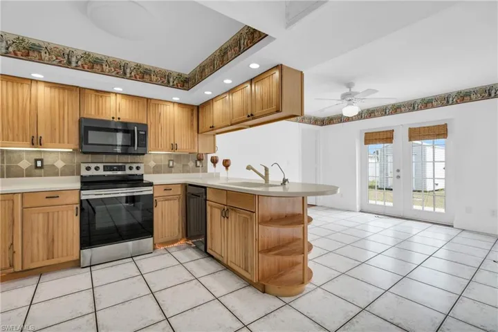 Kitchen with decorative backsplash, electric range, a peninsula, a sink, and dishwasher