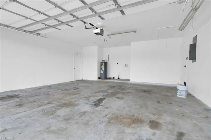 Garage featuring water heater, a garage door opener, and electric panel
