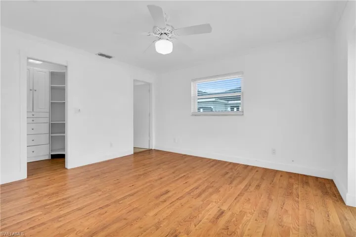 Unfurnished bedroom with visible vents, light wood-style floors, crown molding, and a spacious closet