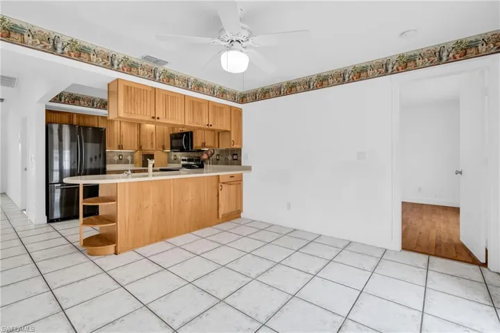 Kitchen featuring visible vents, open shelves, a peninsula, light countertops, and black appliances