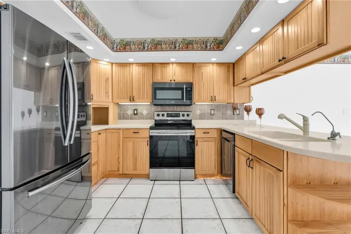 Kitchen featuring light countertops, appliances with stainless steel finishes, a sink, and tasteful backsplash