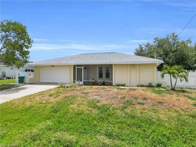 Ranch-style home featuring a garage, fence, a front lawn, concrete driveway, and stucco siding