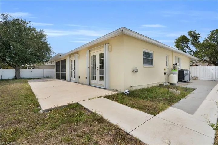 Rear view of property featuring fence, a patio, stucco siding, french doors, and a gate
