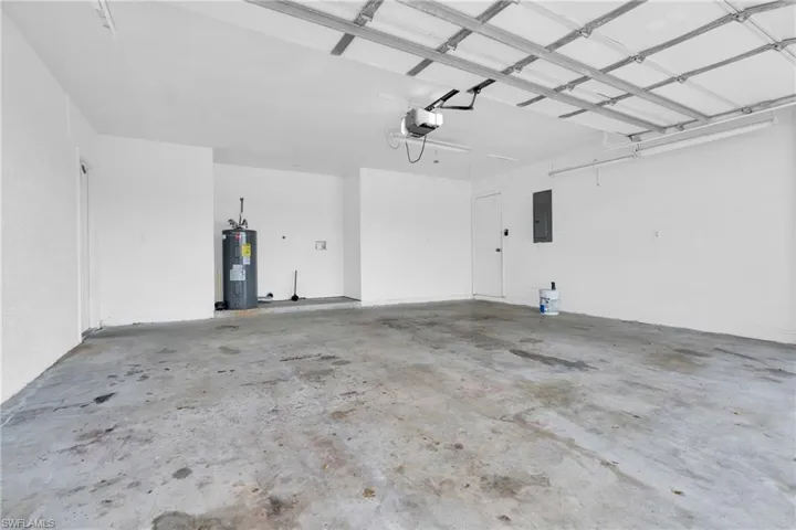 Garage featuring a garage door opener, electric panel, and electric water heater