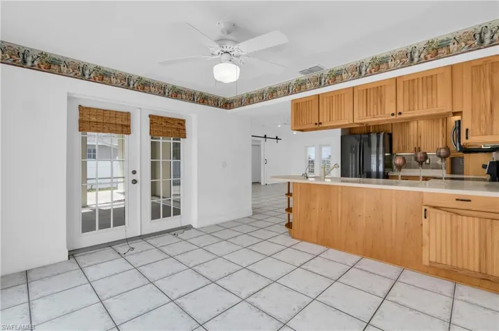 Kitchen with ceiling fan, a barn door, light countertops, freestanding refrigerator, and a peninsula