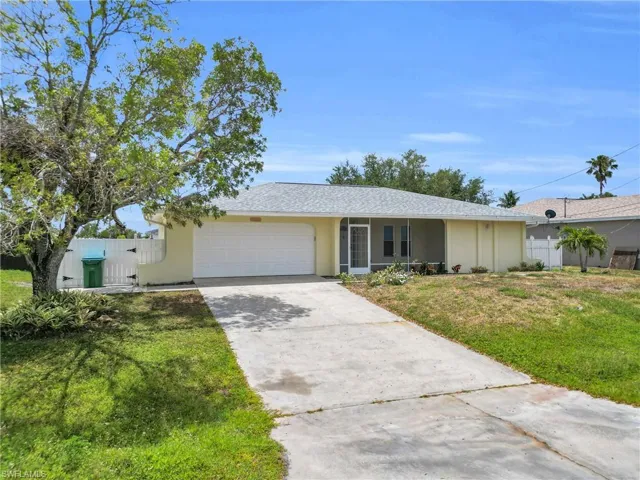 Single story home featuring concrete driveway, fence, a front lawn, and a garage