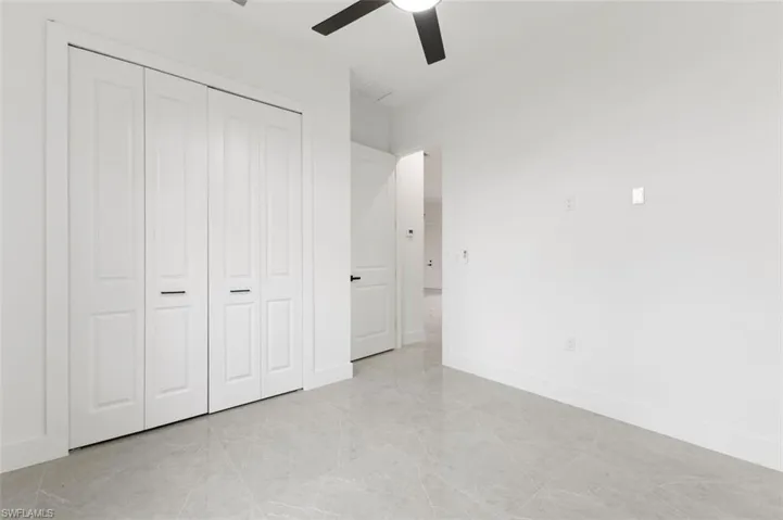 Unfurnished bedroom featuring a closet, ceiling fan, and light tile patterned floors