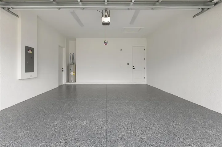 Garage with a garage door opener, electric water heater, and electric panel