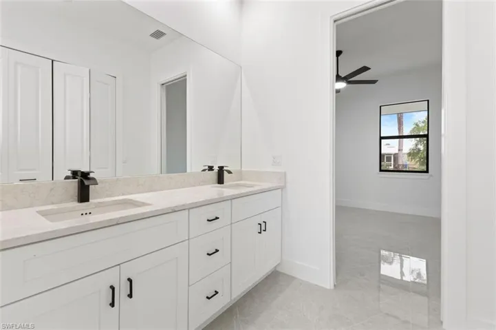 Bathroom featuring dual vanity, ceiling fan, and tile patterned floors