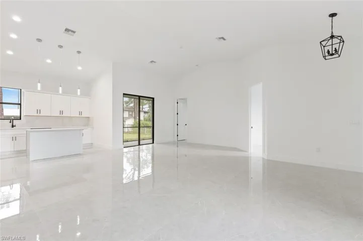 Unfurnished living room with sink, high vaulted ceiling, and light tile patterned floors