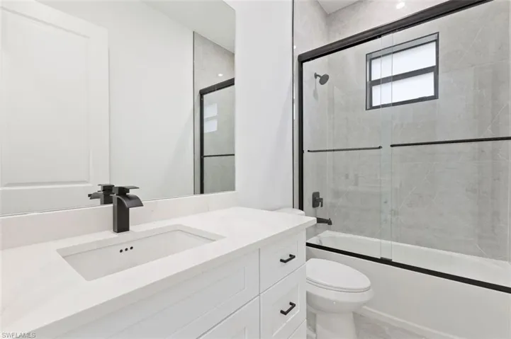 Full bathroom featuring tile patterned floors, toilet, shower / bath combination with glass door, and vanity