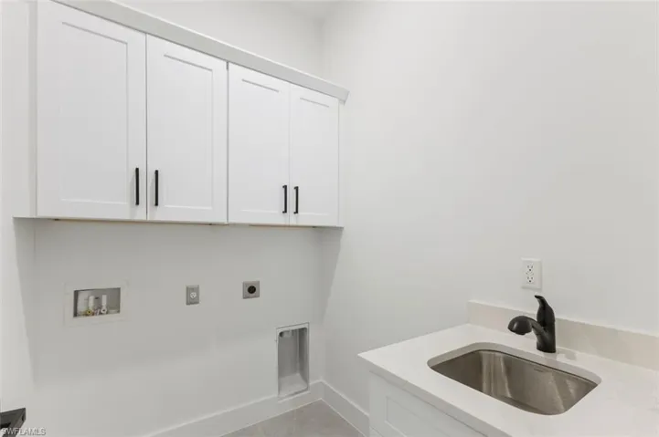 Washroom featuring sink, electric dryer hookup, washer hookup, cabinets, and light tile patterned floors