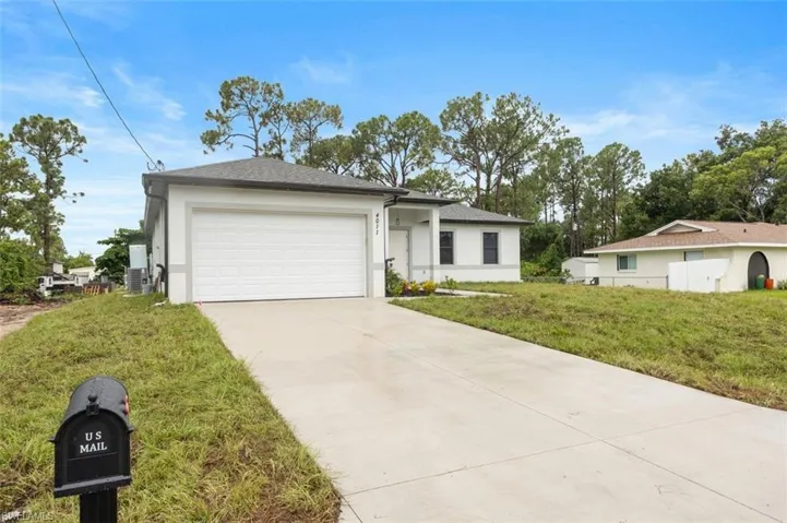 Ranch-style house featuring a garage, central air condition unit, and a front lawn