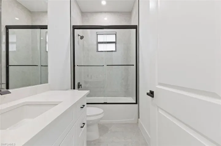 Full bathroom with combined bath / shower with glass door, toilet, tile patterned floors, and vanity