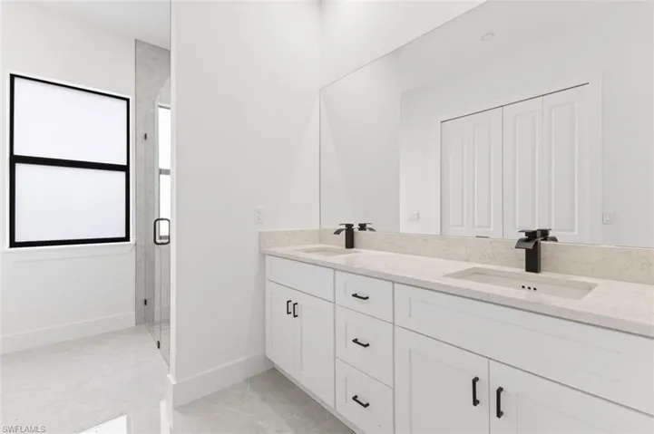 Bathroom with tile patterned flooring, dual vanity, and a shower with shower door