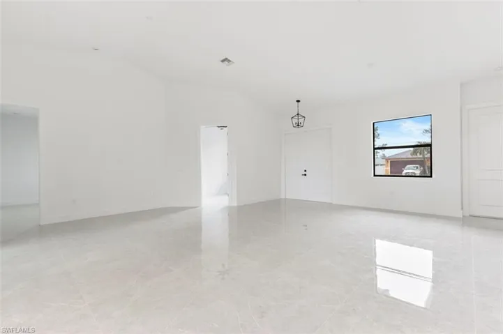 Empty room with vaulted ceiling and light tile patterned flooring