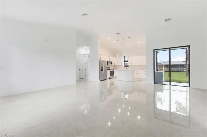 Spare room featuring light tile patterned flooring, sink, and high vaulted ceiling