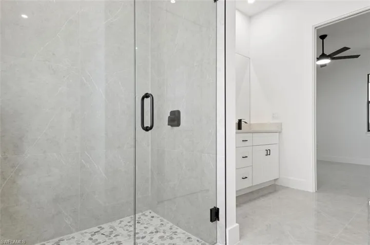 Bathroom with ceiling fan, tile patterned flooring, vanity, and a shower with shower door