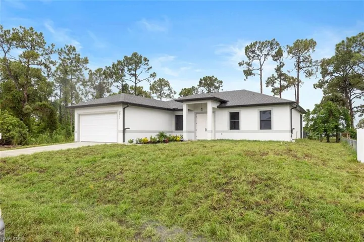 View of front of property with a garage and a front lawn