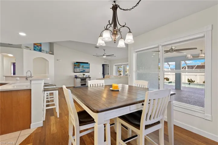 Dining area featuring ceiling fan with notable chandelier, light hardwood / wood-style flooring, a wealth of natural light, and sink