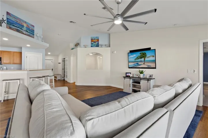Living room with ceiling fan, hardwood / wood-style floors, and vaulted ceiling