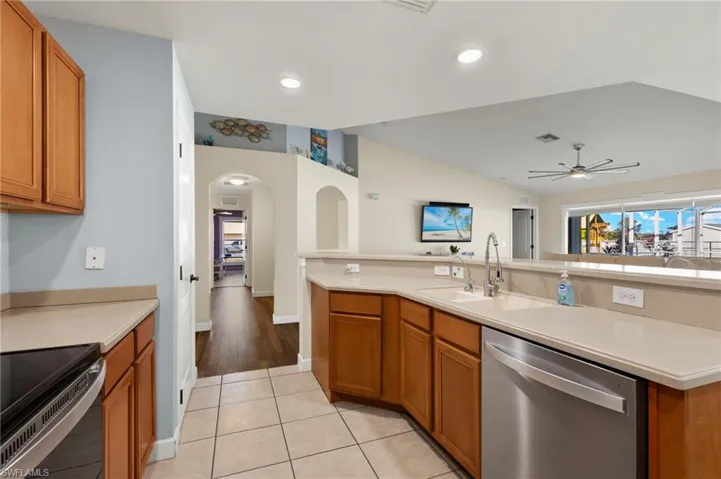 Kitchen featuring lofted ceiling, sink, stainless steel dishwasher, ceiling fan, and electric range oven