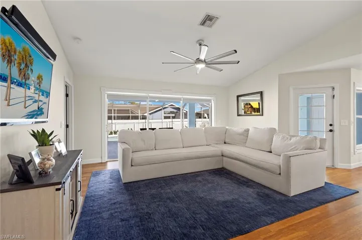 Living room featuring ceiling fan, lofted ceiling, and hardwood / wood-style flooring