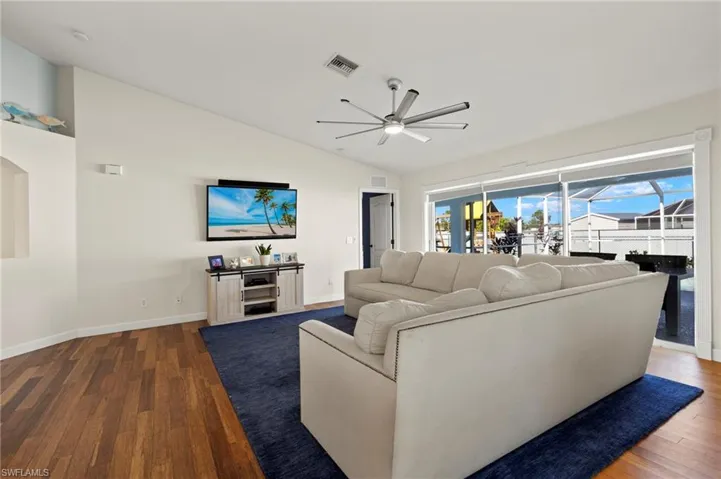 Living room with ceiling fan, wood-type flooring, and vaulted ceiling