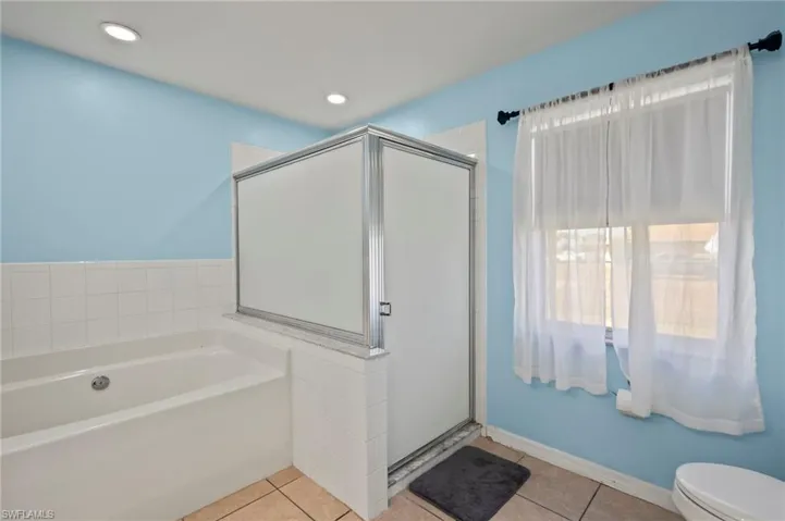 Bathroom featuring tile patterned floors, toilet, and plus walk in shower