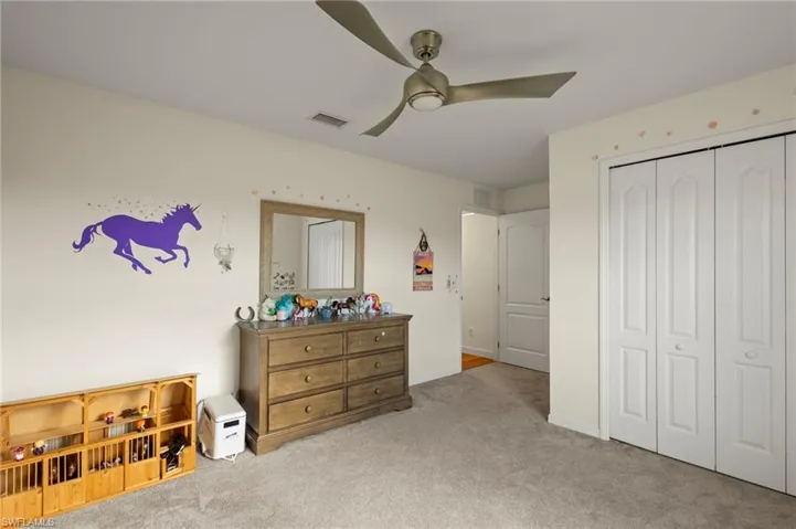 Carpeted bedroom featuring ceiling fan and a closet