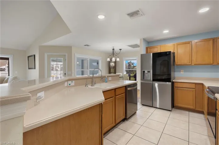 Kitchen with sink, stainless steel appliances, plenty of natural light, and an inviting chandelier