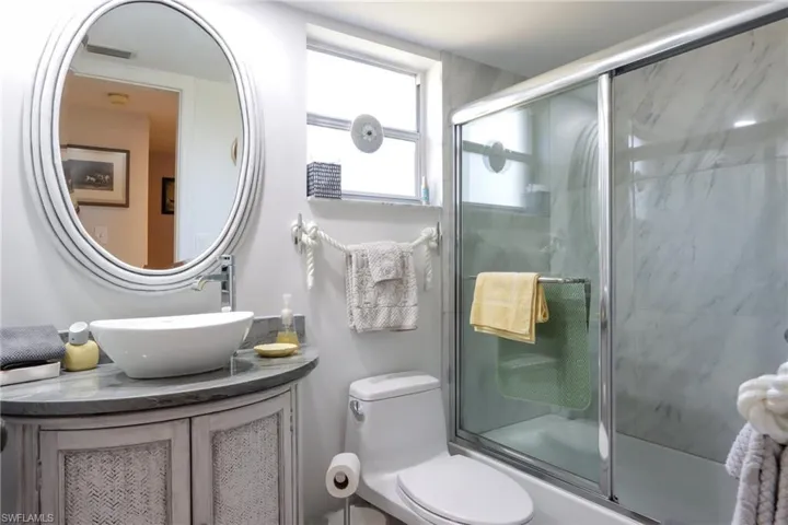 Bathroom with vanity and combined bath / shower with glass door