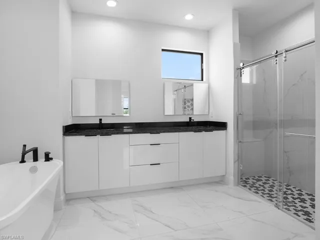 Bathroom with dual vanity, tile patterned flooring, a healthy amount of sunlight, and separate shower and tub
