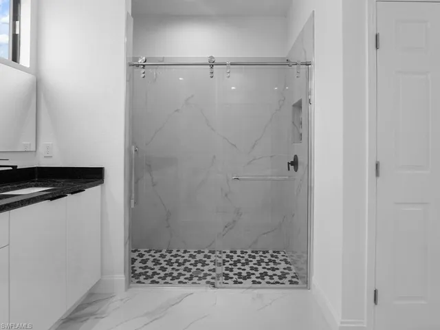 Bathroom featuring tiled shower, tile patterned flooring, and vanity