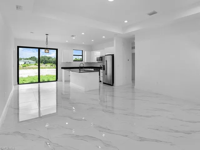 Empty room with sink, a tray ceiling, and light tile patterned floors