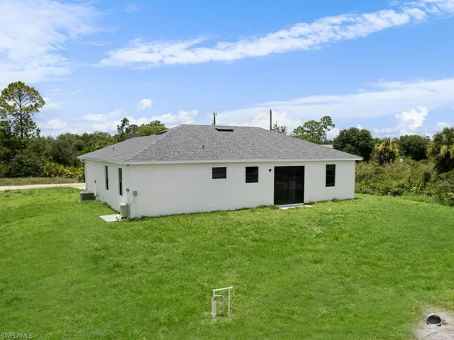 Rear view of house featuring cooling unit and a lawn