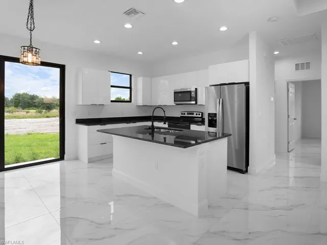 Kitchen featuring sink, a kitchen island with sink, light tile patterned floors, and stainless steel appliances