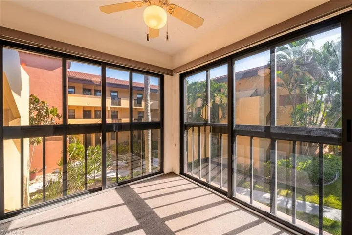 Enclosed sunroom featuring expansive sliding glass panels overlooking landscaped courtyard.