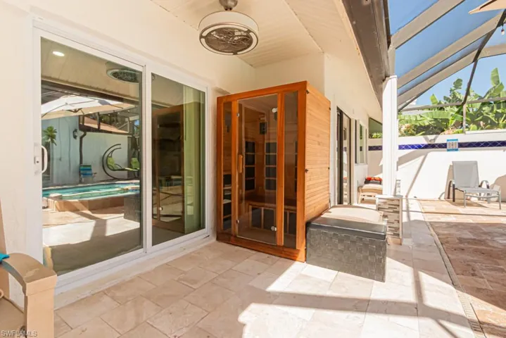View of patio / terrace featuring glass enclosure and a hot tub