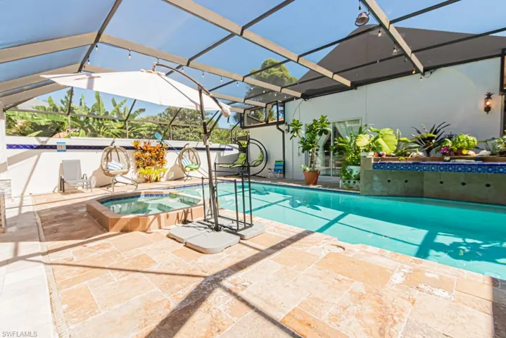 View of pool featuring a lanai, a patio area, a pool with connected hot tub, and a sunroom