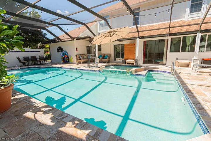 View of pool with a pool with connected hot tub, a patio, glass enclosure, a sunroom, and outdoor dining area